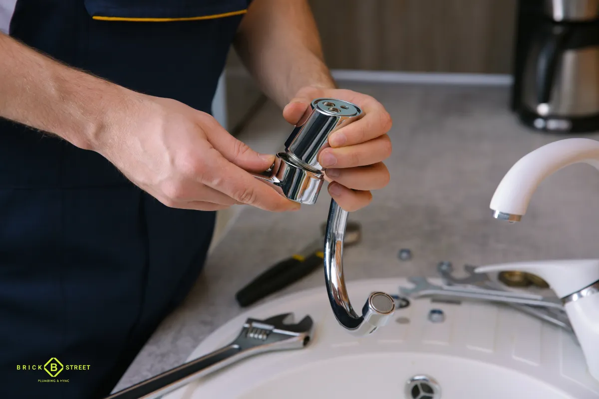 Plumber fixing a leaking bathroom faucet